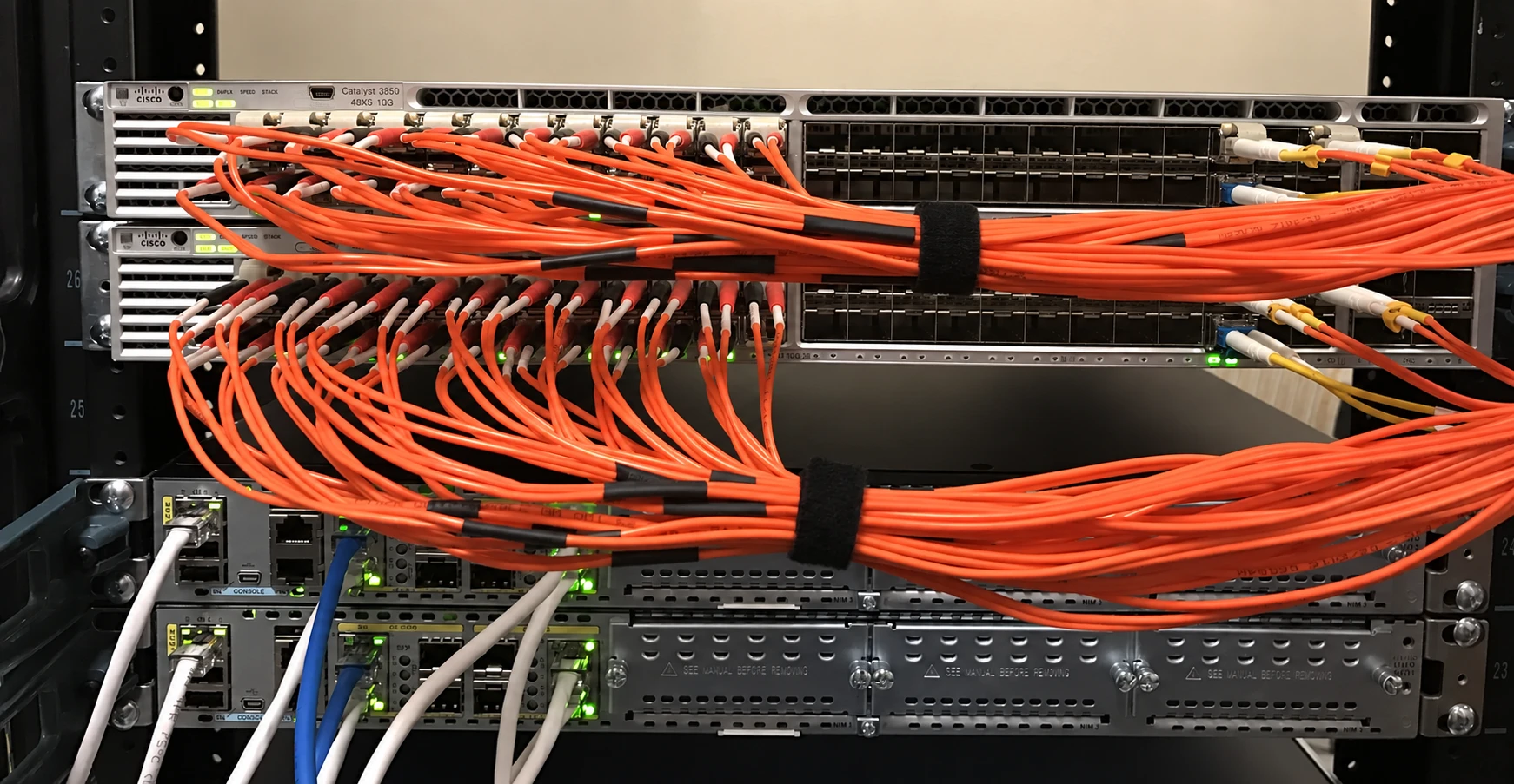 Orange fiber connections running across network switches in an equipment rack